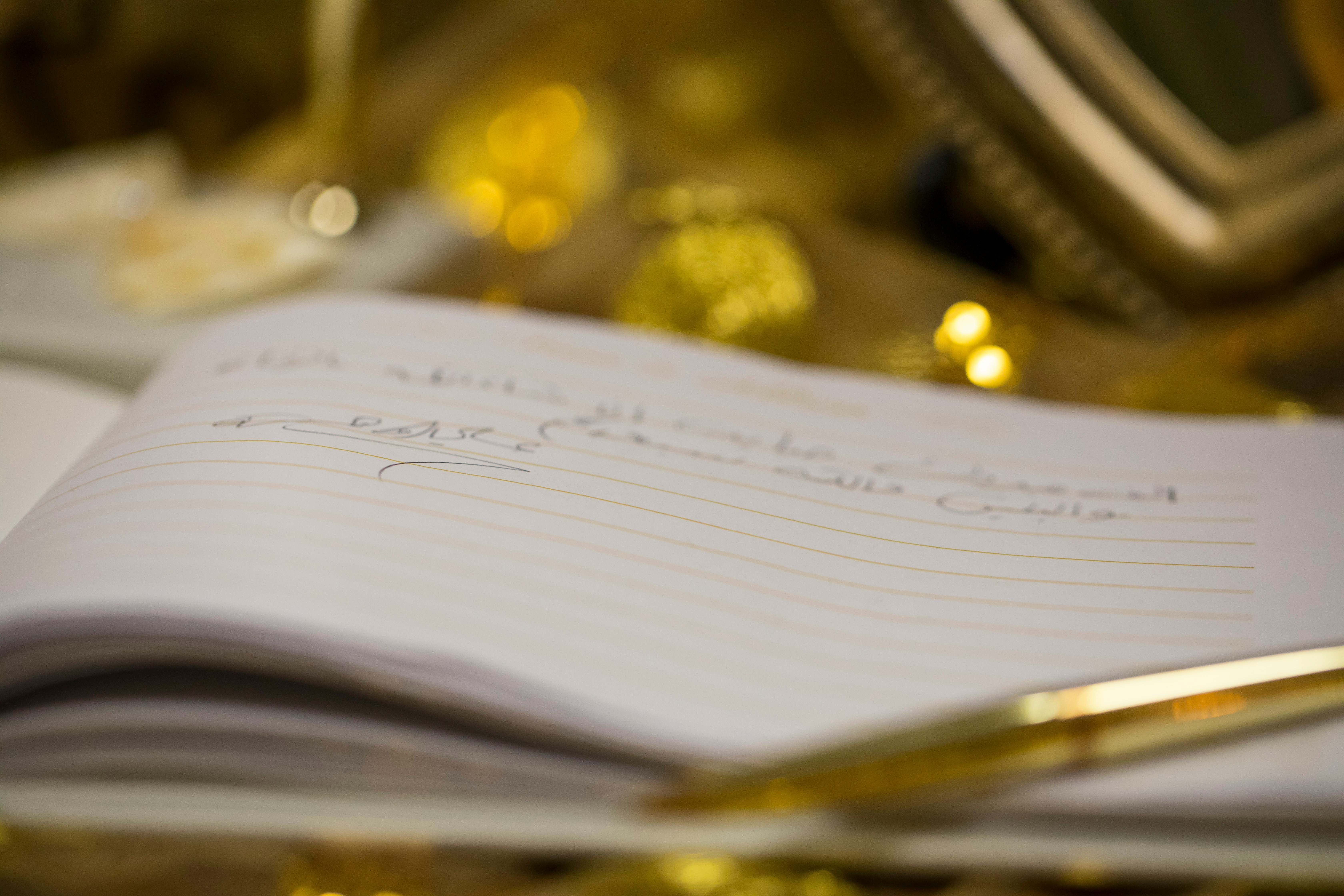 A golden pen resting on a notebook with writing